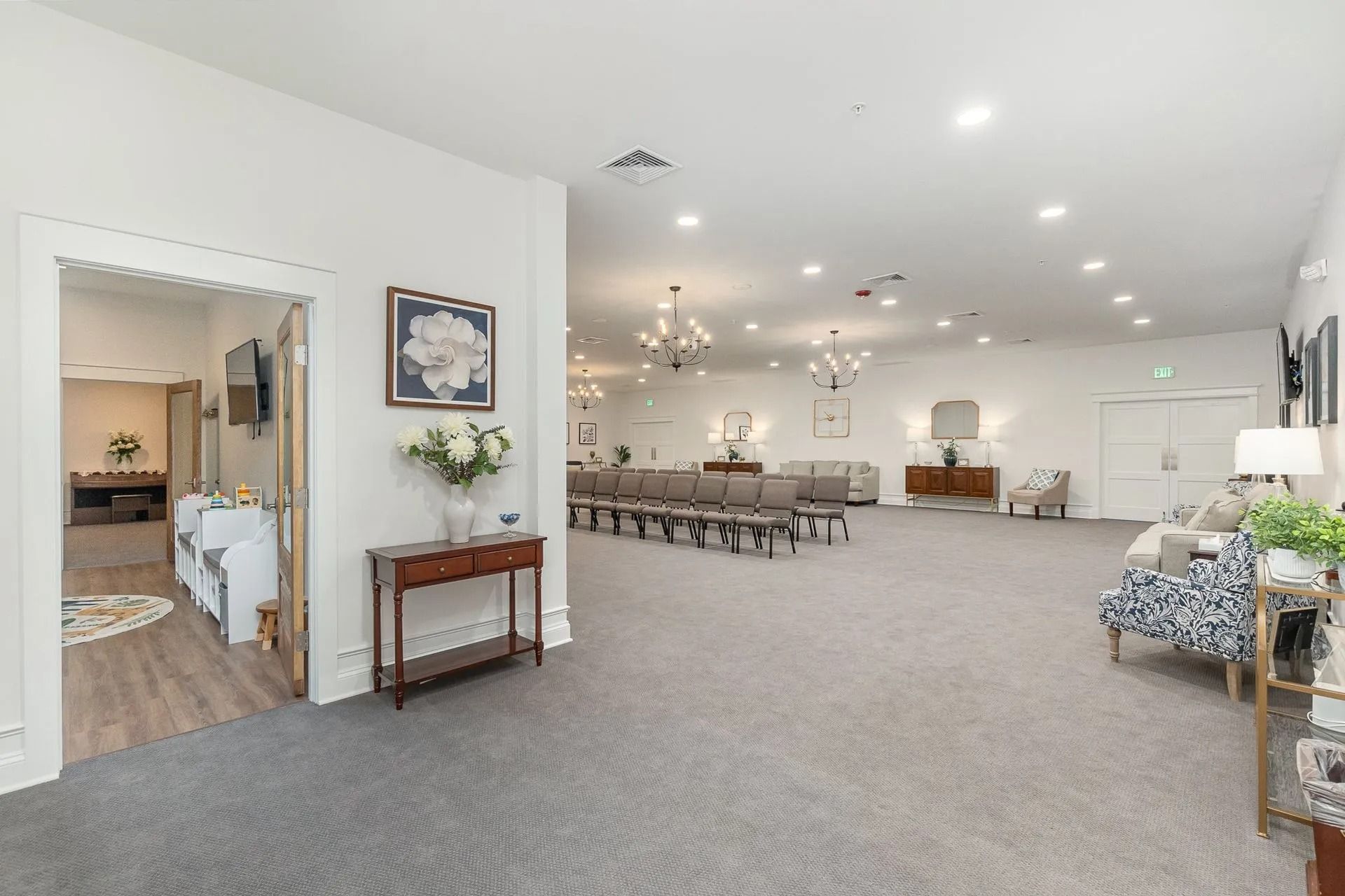 An empty, well-lit room with a doorway, chairs, and decorations; possibly an event space.
