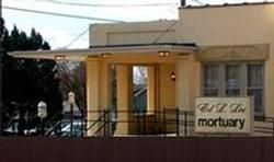 Exterior view of Ed L. Zare mortuary building; beige walls, sign on the lawn.