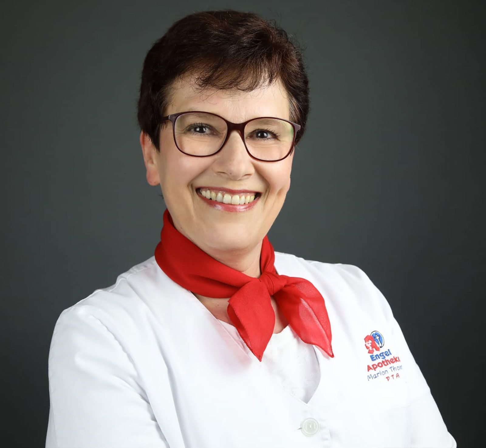 Eine Frau mit Brille und rotem Schal lächelt in die Kamera