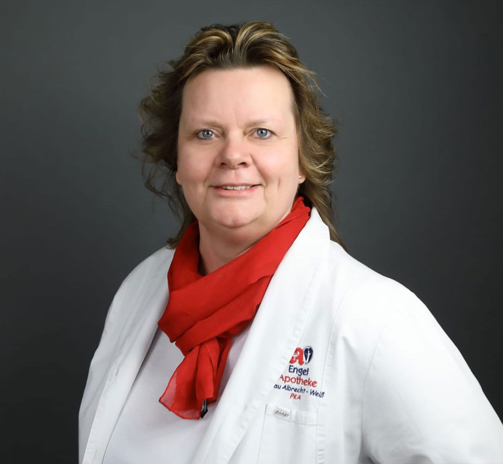 Eine Frau in einem weißen Laborkittel und einem roten Schal