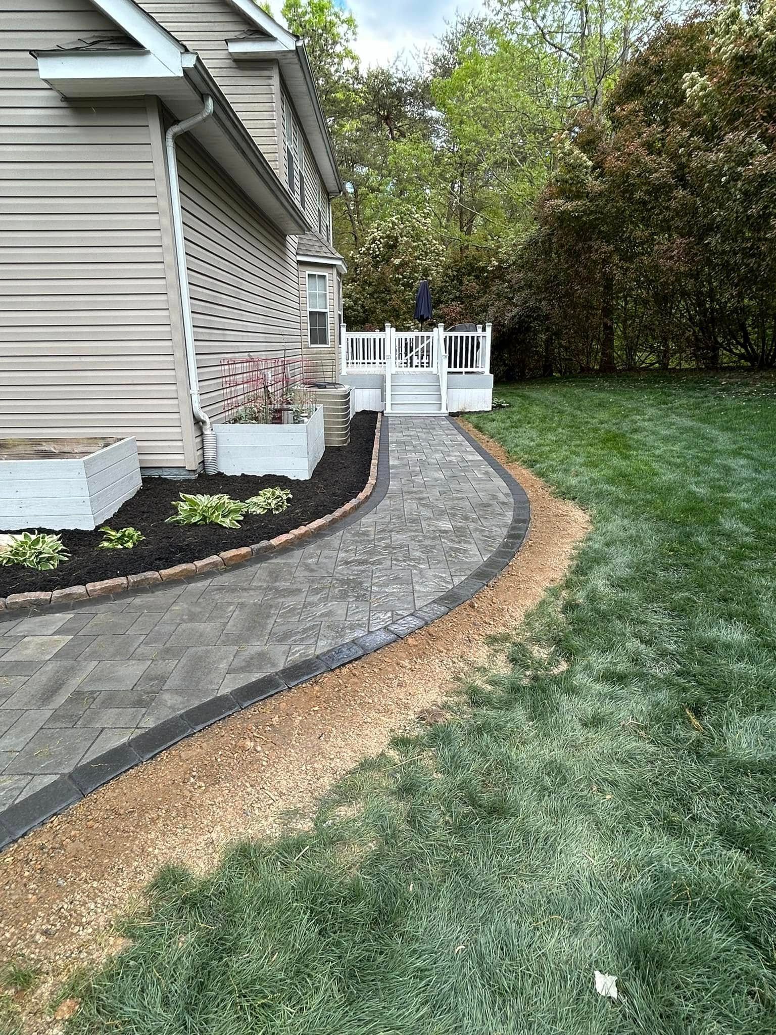 There is a walkway leading to a deck in the backyard of a house.