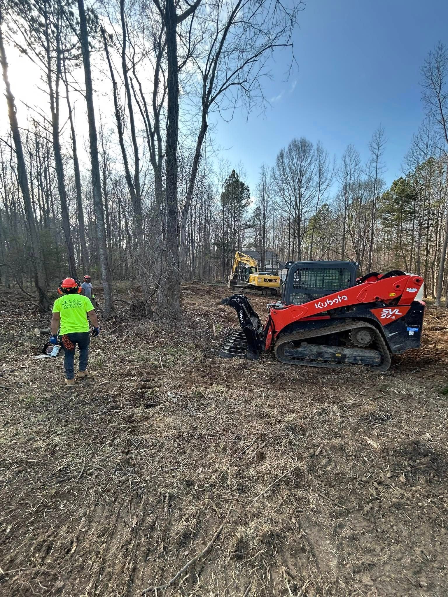 A man is walking in the woods next to a bulldozer.