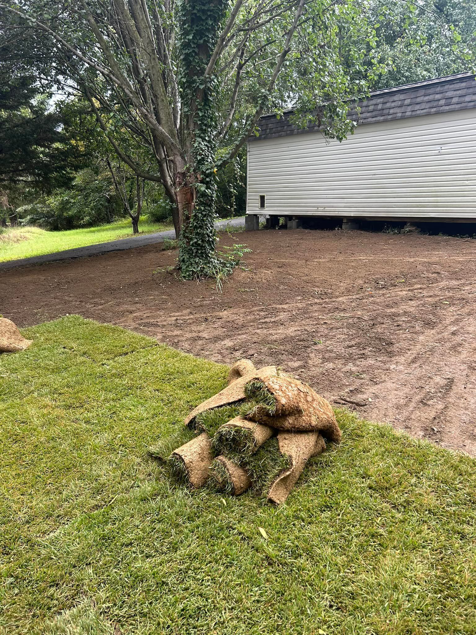 A pile of grass is sitting on top of a lush green lawn in front of a house.