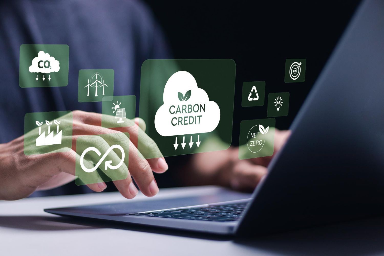 A person is typing on a laptop computer with a carbon credit icon on the screen.