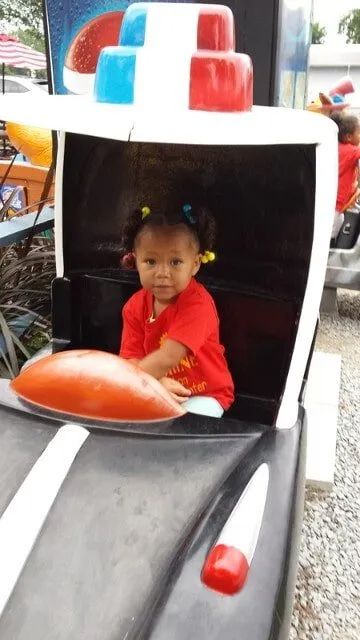 Girl Smiling In Toy Car — York, PA — Sunshine Christian Daycare / Learning Center