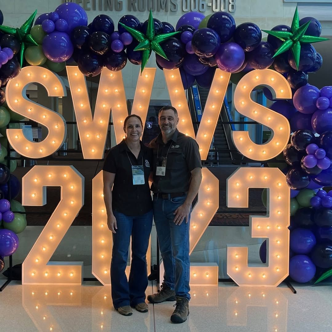 Two people standing in front of a sign that says swws 2013