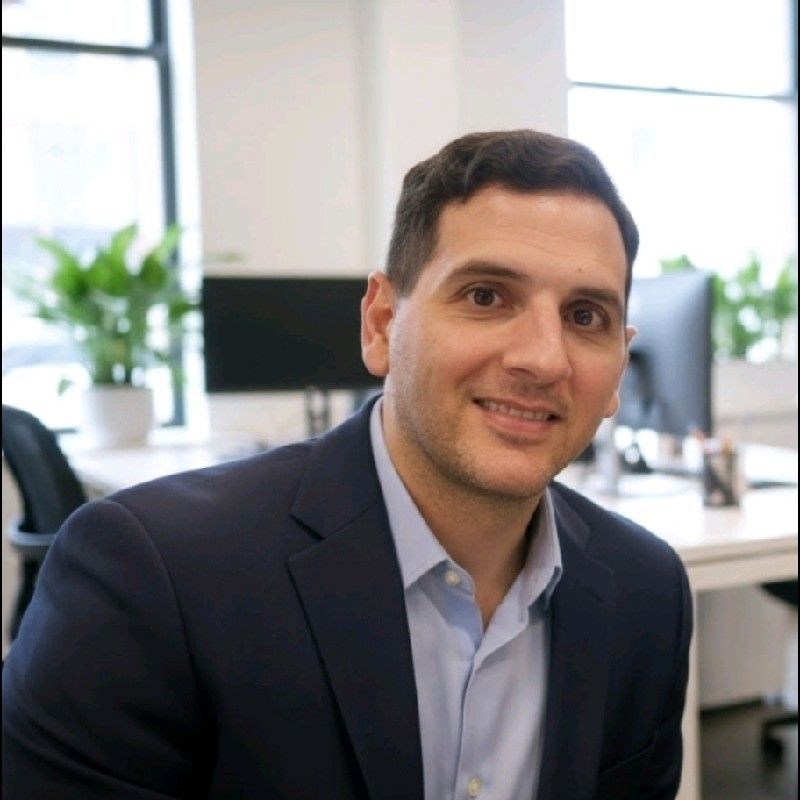 A man in a suit and tie is standing in front of a red wall.