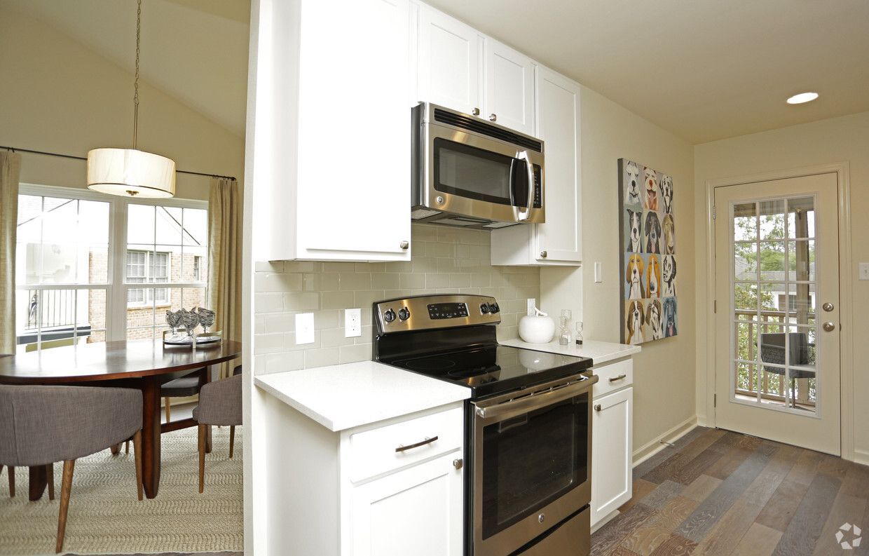 Modern kitchen with white cabinets, stainless steel appliances, and dark wood floors.