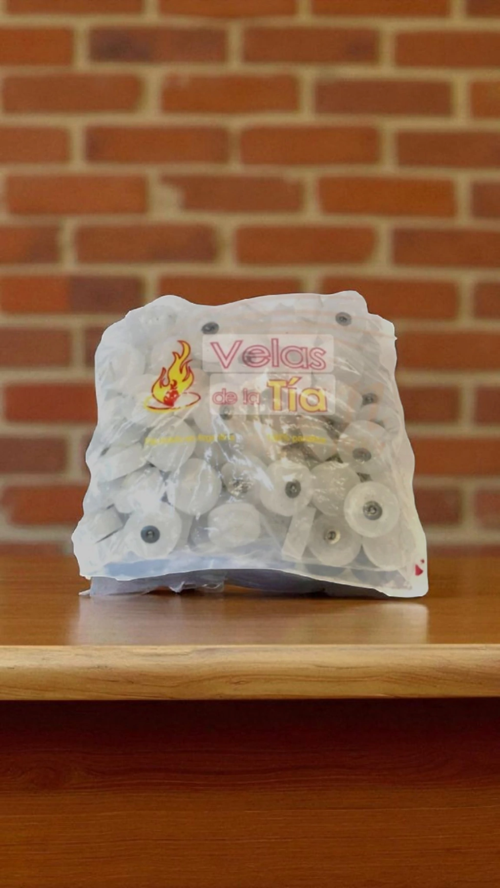 Bolsa de objetos blancos con forma de carrete sobre una mesa de madera, apoyada contra una pared de ladrillos.