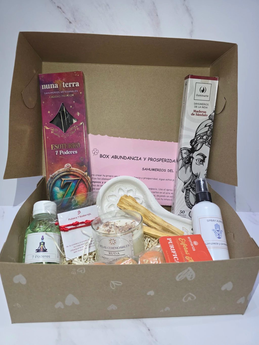 Caja abierta con diversos artículos espirituales: incienso, cristales, velas y una varilla para sahumar.