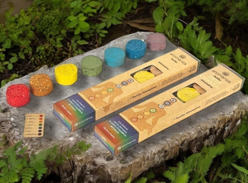 Conos y cajas de incienso de colores dispuestos sobre una roca en un entorno de jardín.