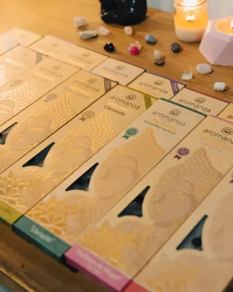 Una fila de cajas de incienso de varios colores con una planta al fondo.