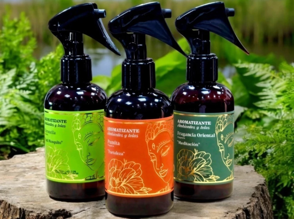 Tres botellas de spray con etiquetas de colores, frente a la vegetación.