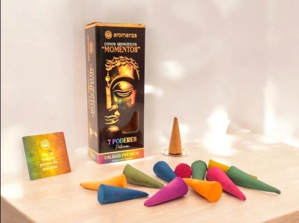 Conos de incienso en varios colores y caja con Buda sobre mesa.