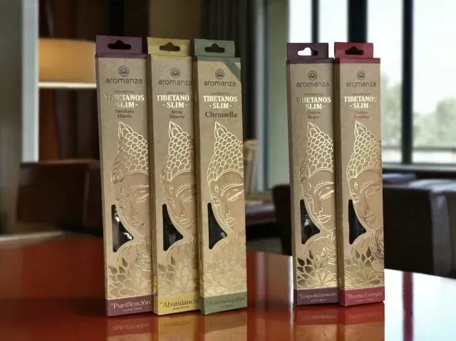 Varitas de incienso en cajas decorativas sobre una mesa en una habitación con una lámpara y estanterías.