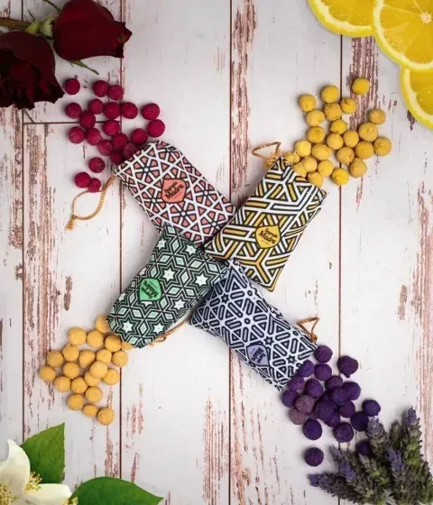 Cuatro bolsas estampadas con esferas de colores derramándose, rodeadas de frutas y flores.