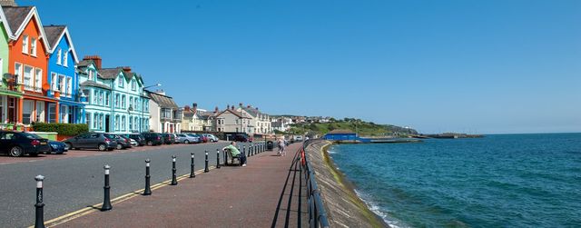 The iconic clock tower standing proudly on the Whitehead promenade in Northern Ireland, overlooking the sea on a sunny day.