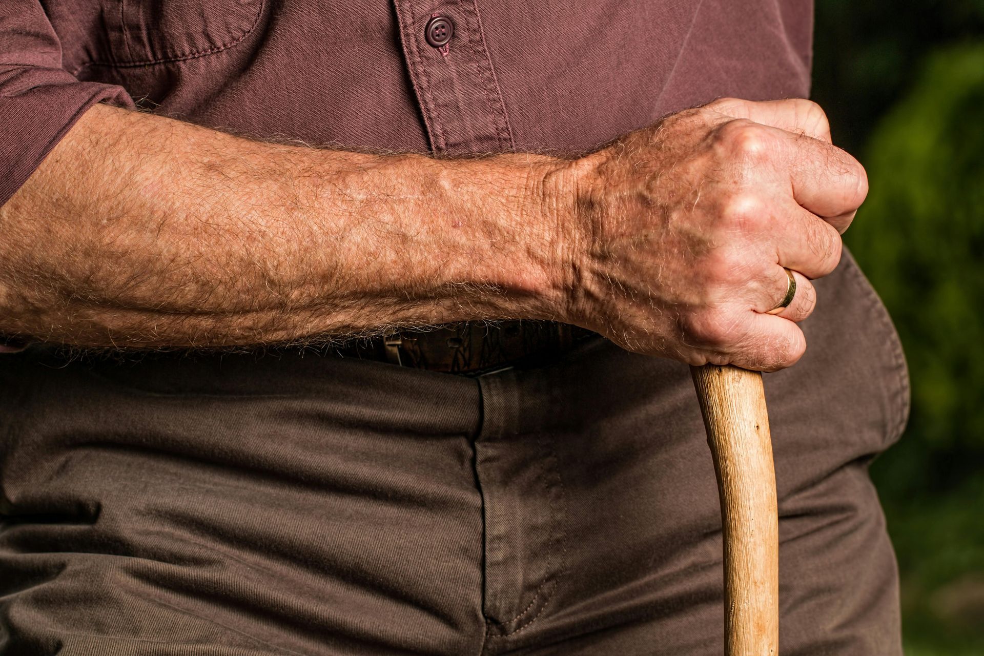 An elderly man is holding a cane in his hand.