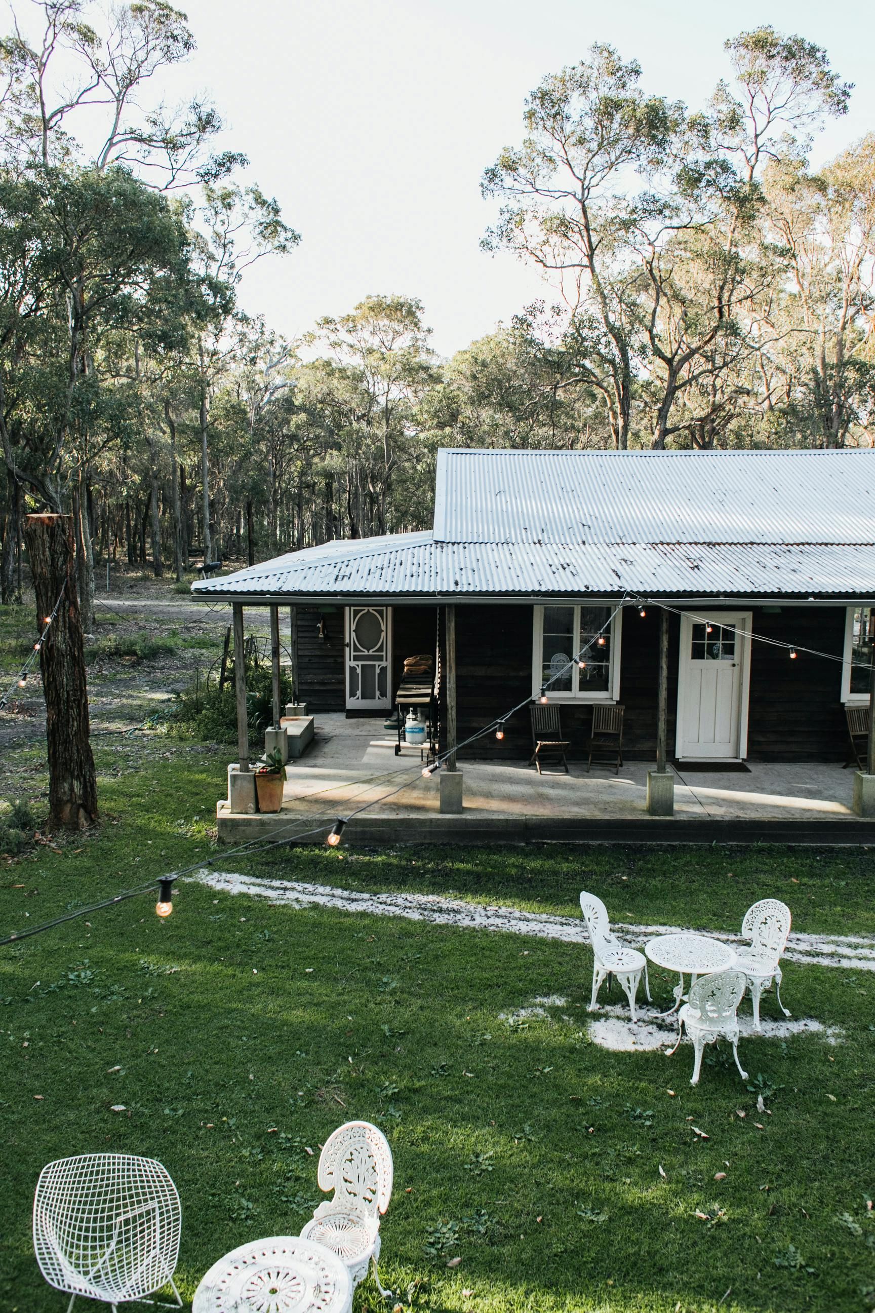 A small house with a porch and a table and chairs in front of it.