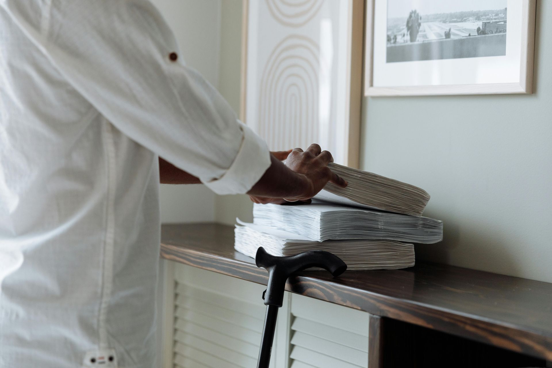 A man with a cane is standing next to a stack of books.