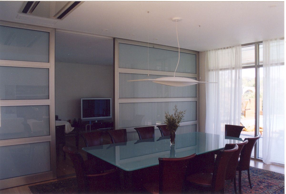 Un comedor con una mesa de cristal y sillas.