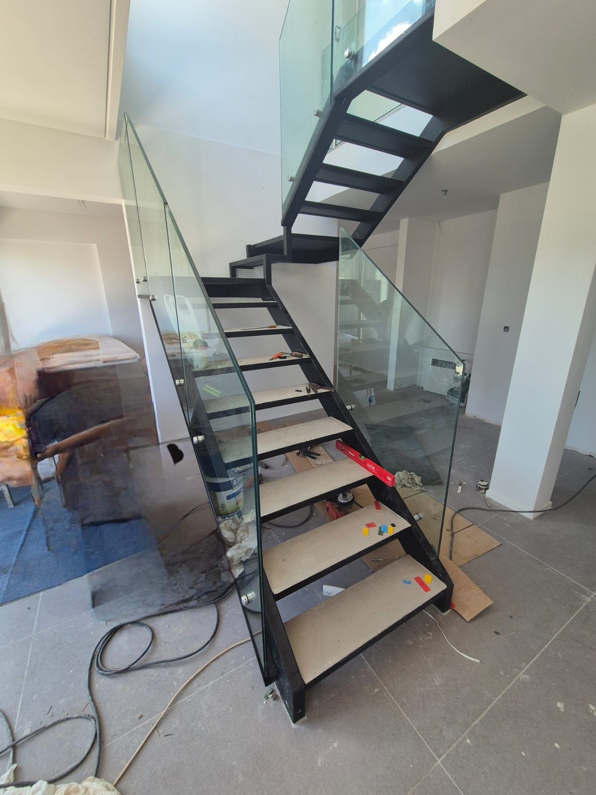 Se está construyendo una escalera con barandilla de cristal en una habitación.