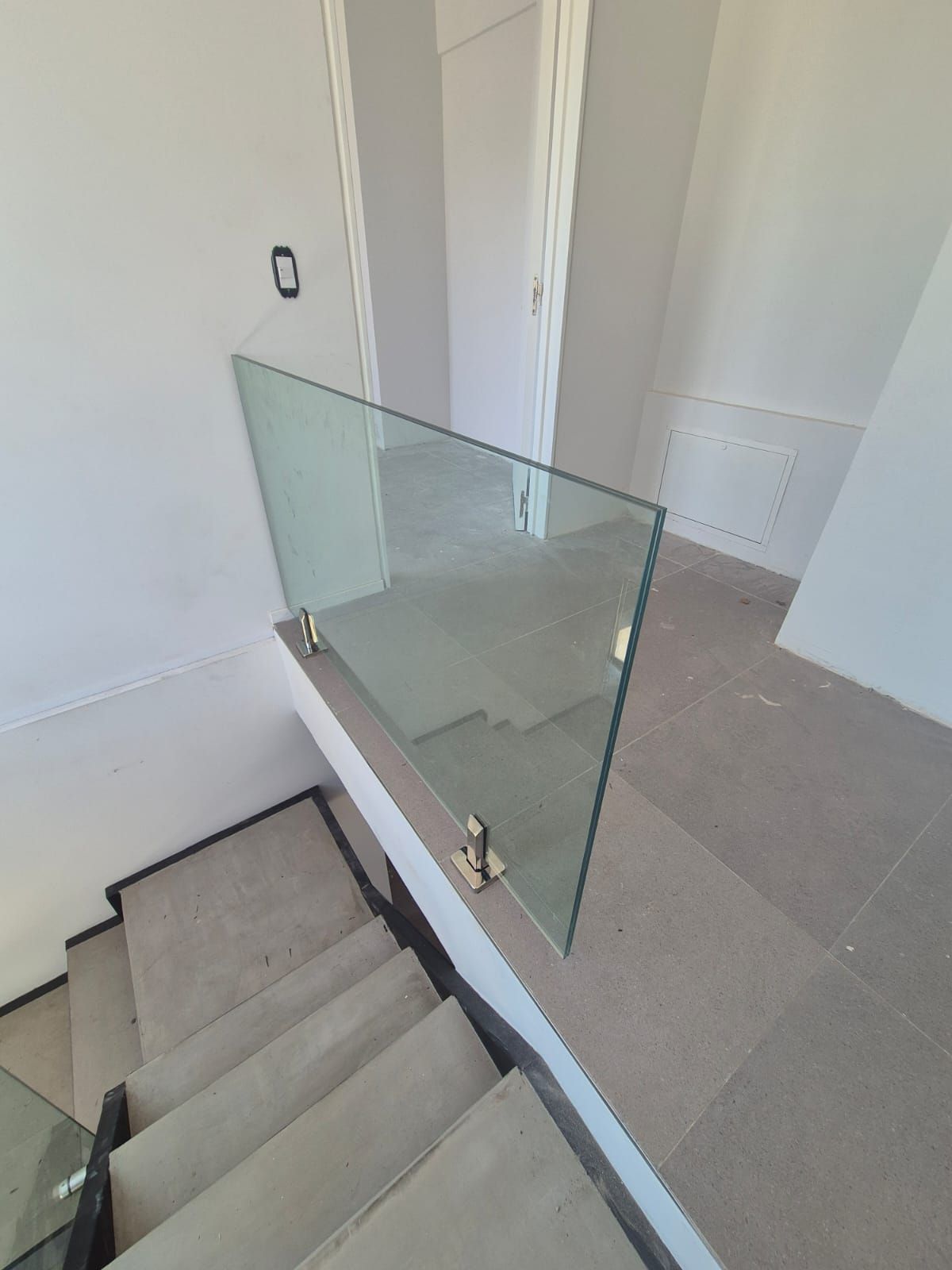 Una escalera con barandilla de cristal y suelo moqueta.