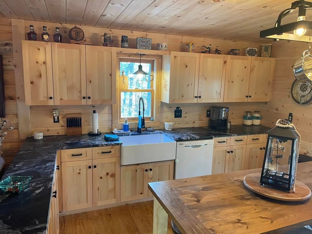 Rustic kitchen with light wood cabinets, dark countertops, and a farmhouse sink.