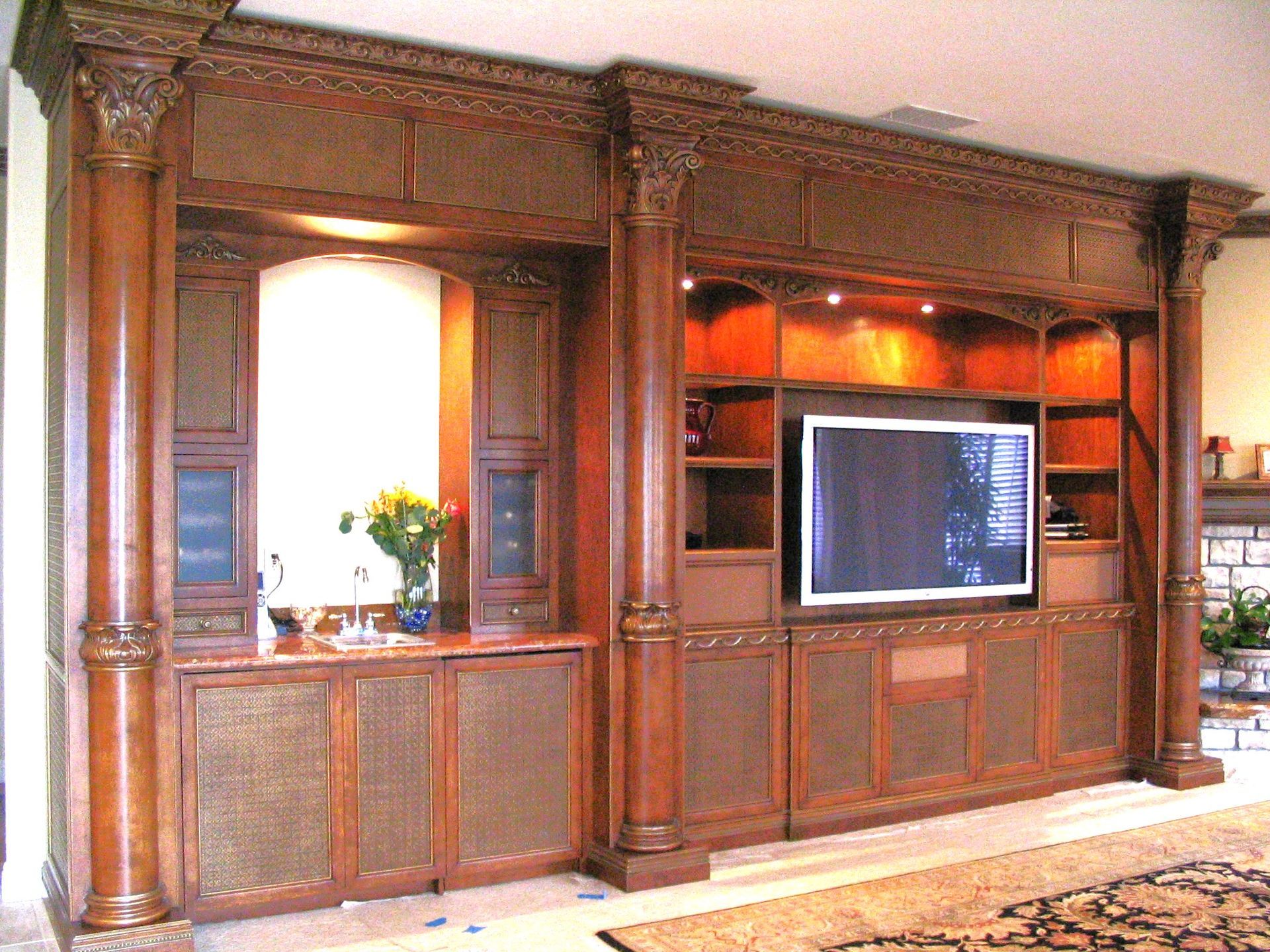 Wooden entertainment center with TV, built-in shelving, and fluted columns.