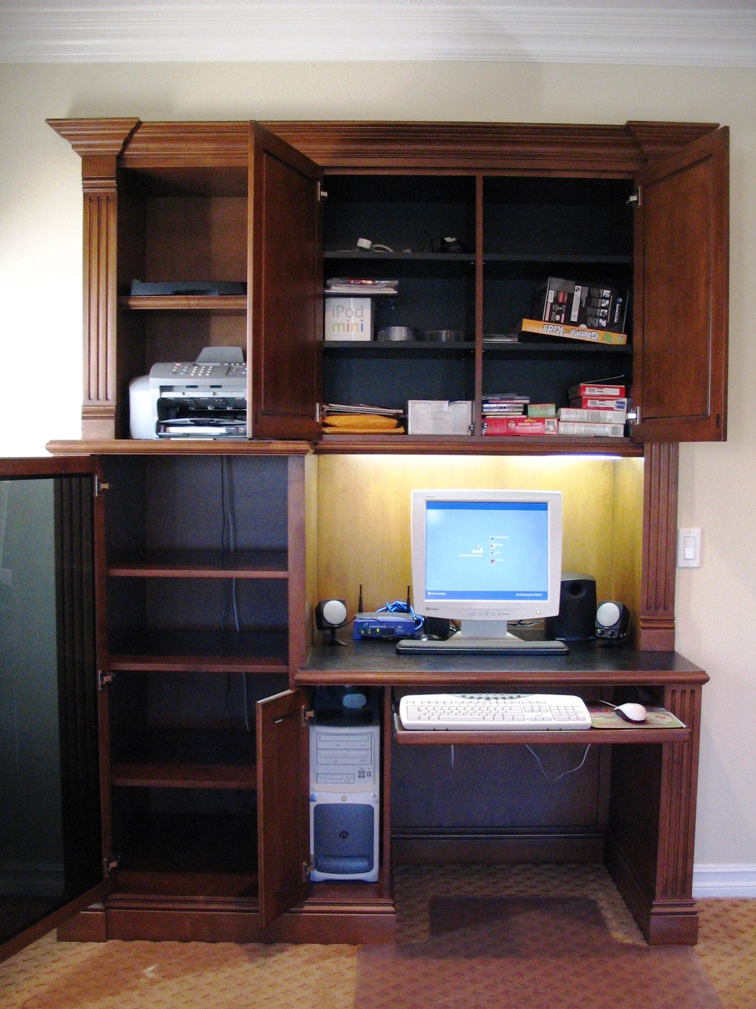 Wooden computer desk with open cabinets and a printer.