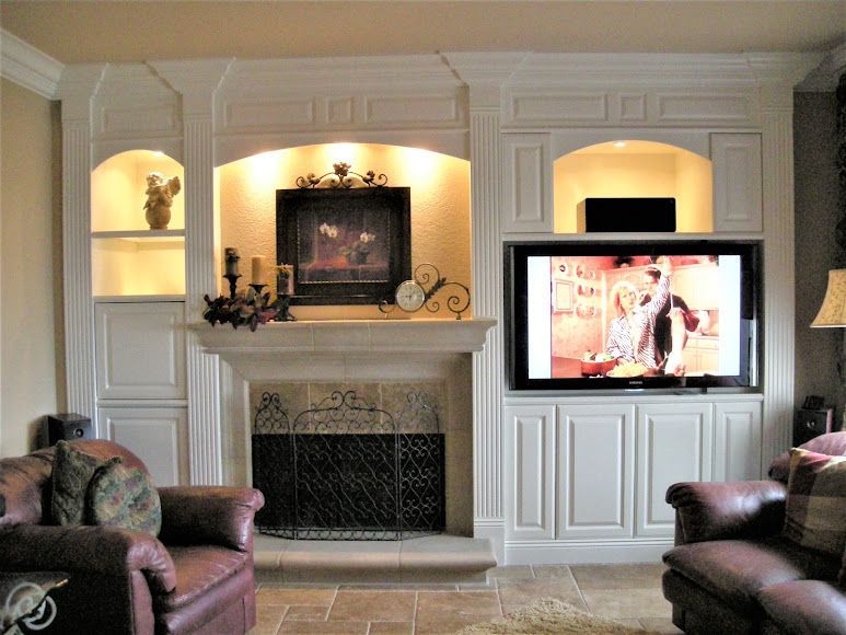 Living room with built-in cabinetry surrounding a fireplace and TV. Brown leather chairs are in front of the setup.