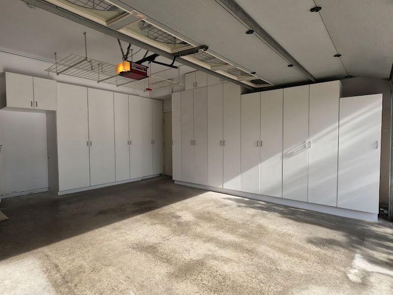 Built-in white bookshelves flank a stone fireplace with a TV above, dark wood beams, and a patterned rug.