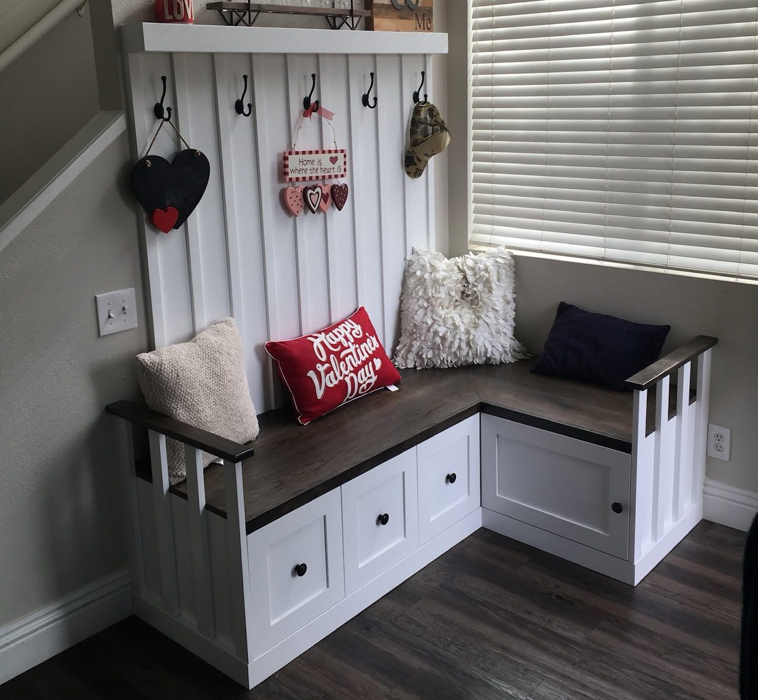 Built-in white media center with TV, fireplace, and shelves with wood backing; a person on screen.