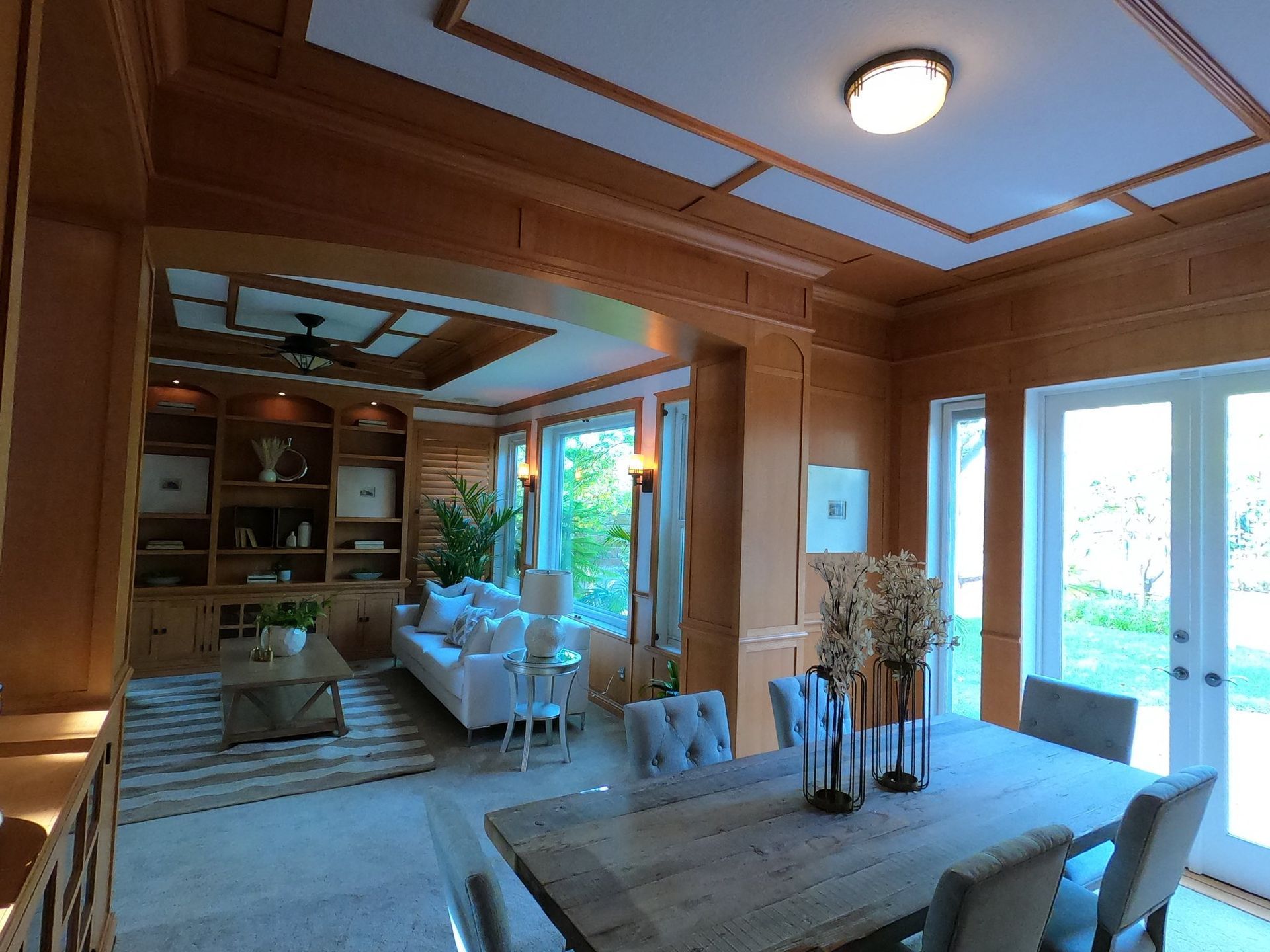 Dining room with wooden paneling, table, chairs, and view into the living room.