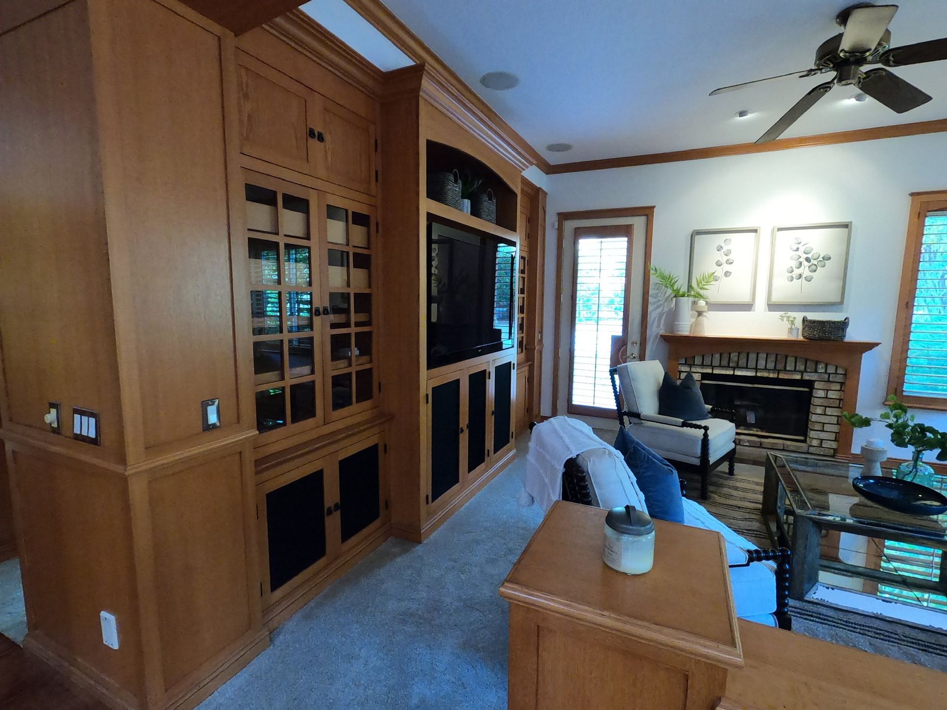 Living room with wood built-ins, fireplace, and beige carpet.