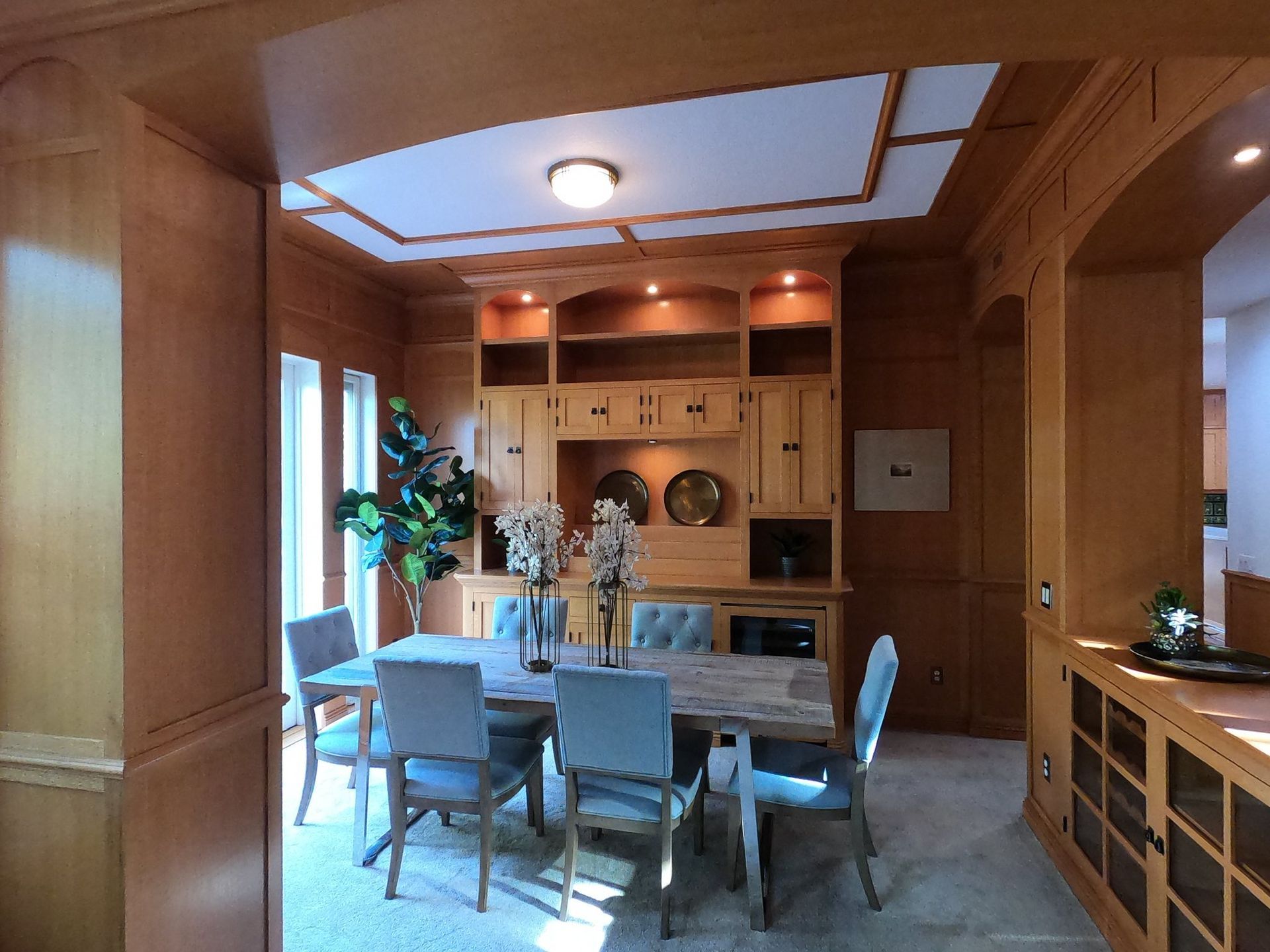 Dining room with light wood paneling, built-in cabinetry, table, chairs.