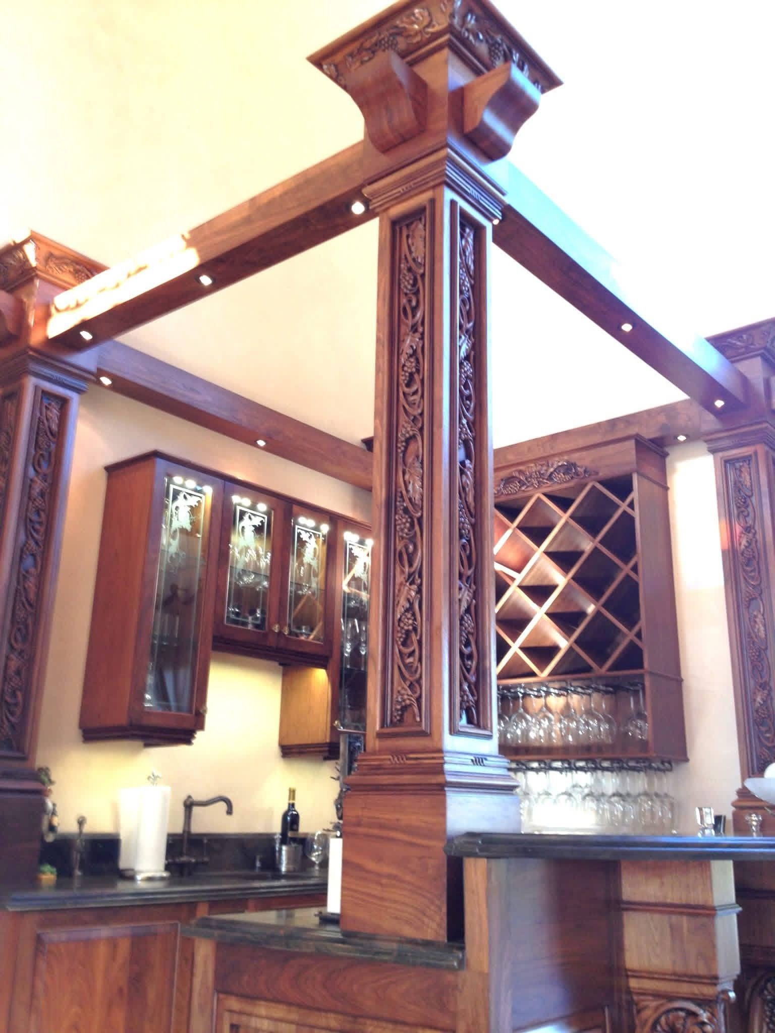 Ornate wooden kitchen island with cabinets, bar, and carved pillar details.