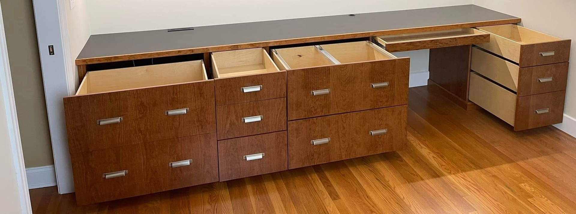 Empty, white walk-in closet with shelves, drawers, and hanging rods; wood flooring.