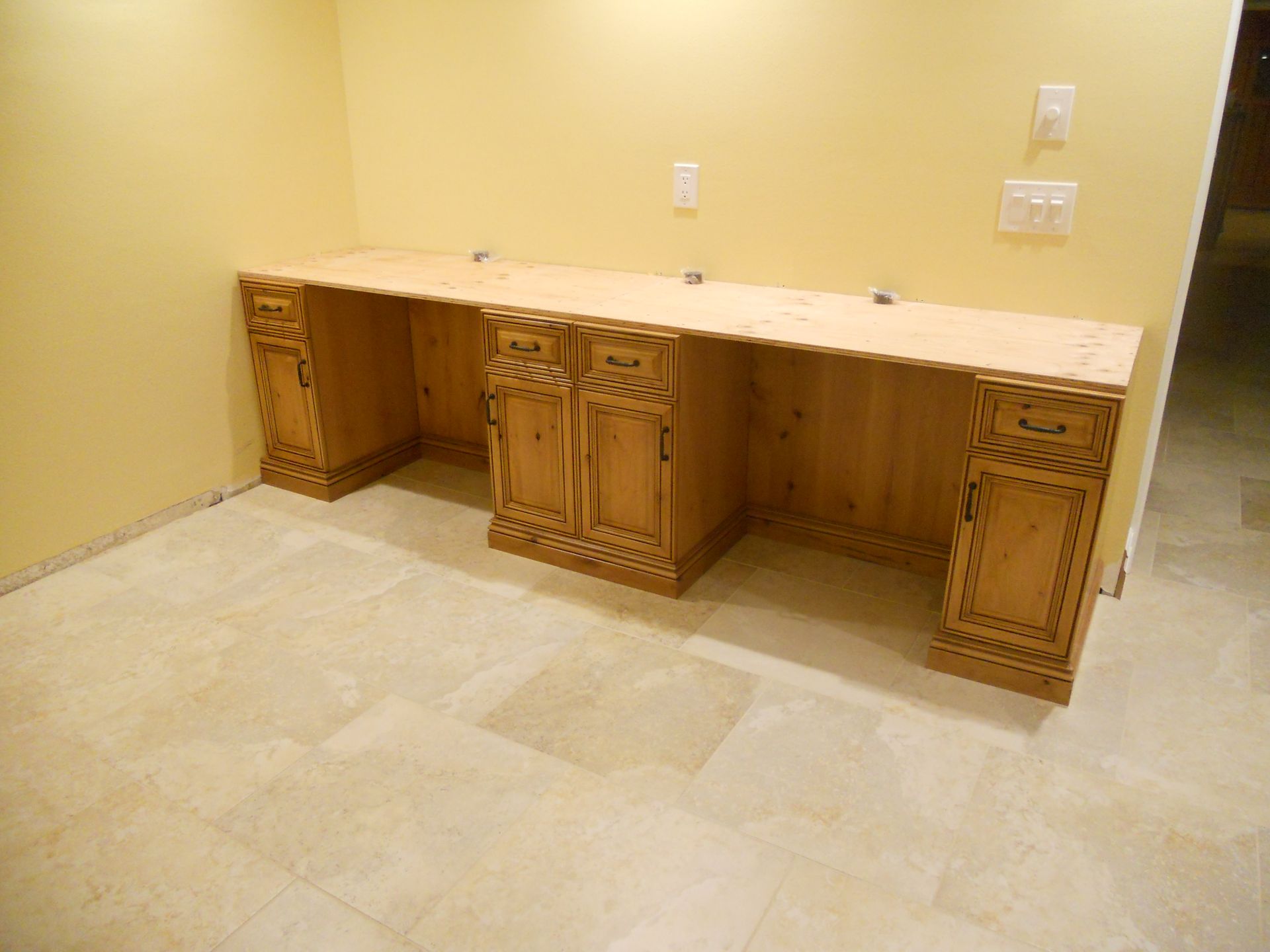Wooden vanity with carved details against a light yellow wall and tiled floor.