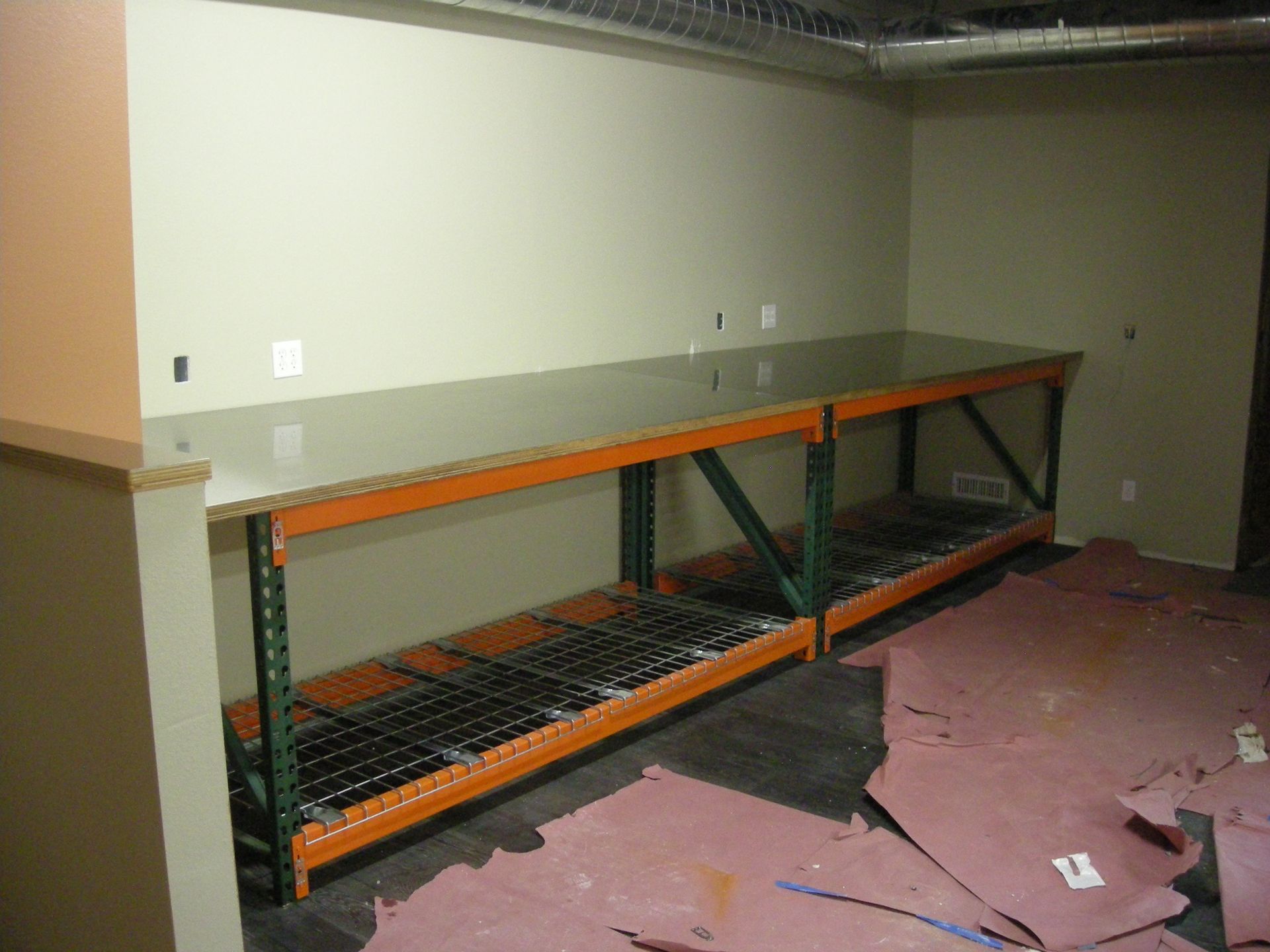 Two long, metal warehouse shelves against a light green wall.