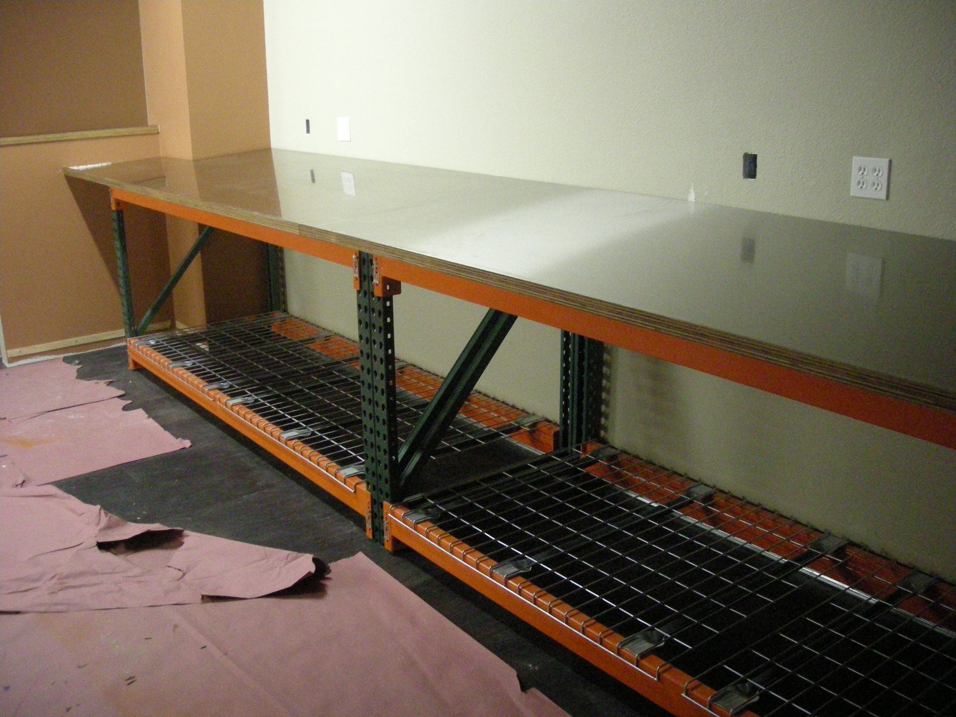 Long, orange industrial shelving unit with a shiny, reflective surface.