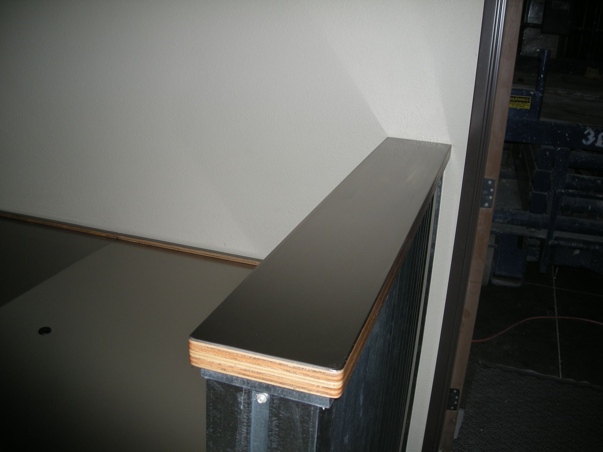 A long, dark-topped handrail against a light-colored wall.