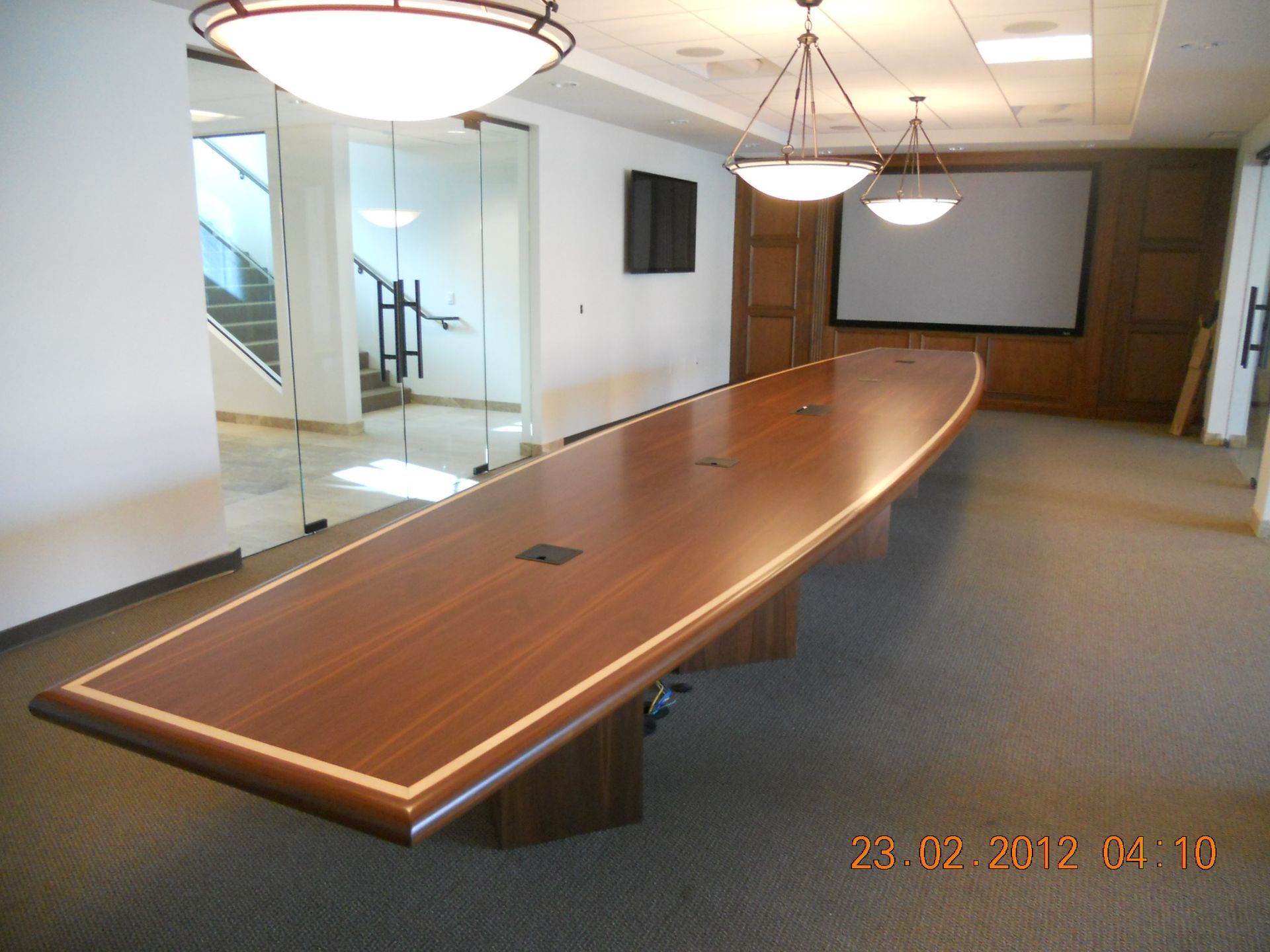 Conference room with a long, wood table, and a projector screen.
