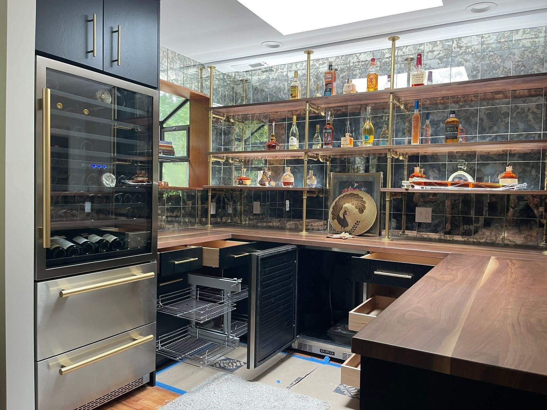 Custom bar with wine fridge, shelving with liquor bottles, wood countertop, and black cabinets.