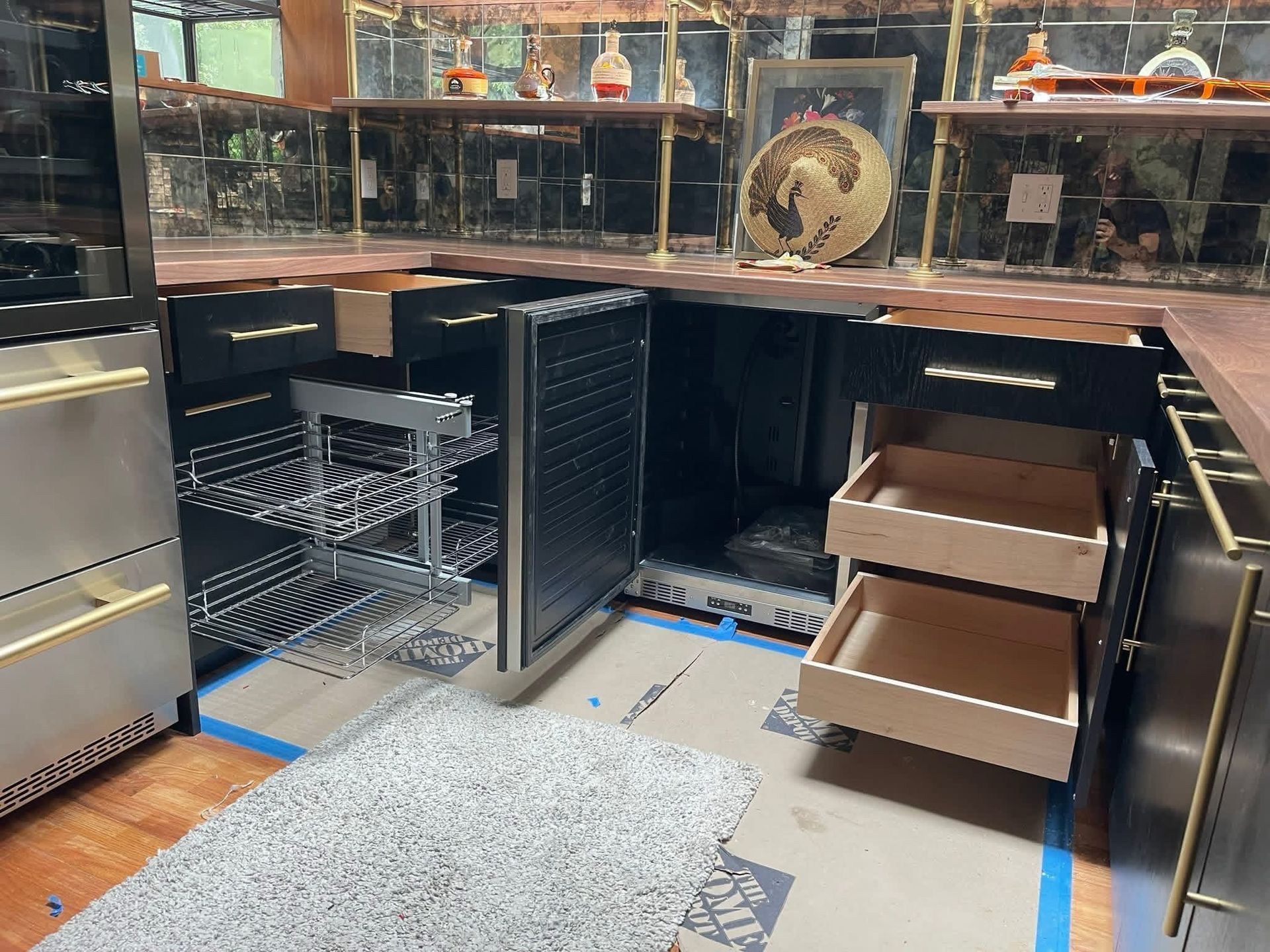 Kitchen with open drawers and a wine rack. Metallic accents, wood countertop, and partially completed construction.