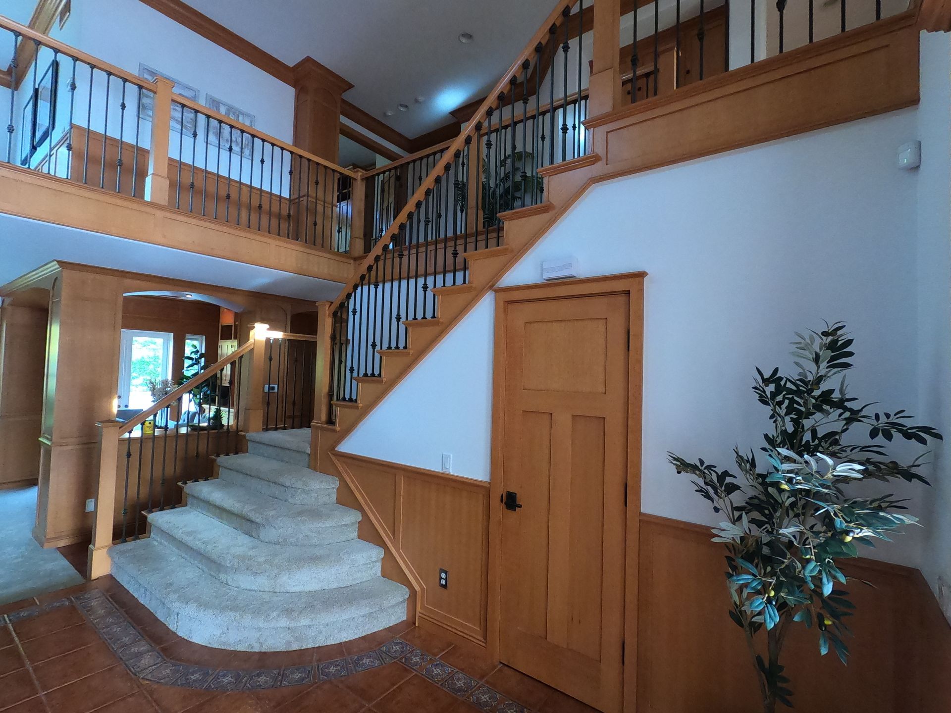 Spacious wooden foyer with staircase and balcony. 