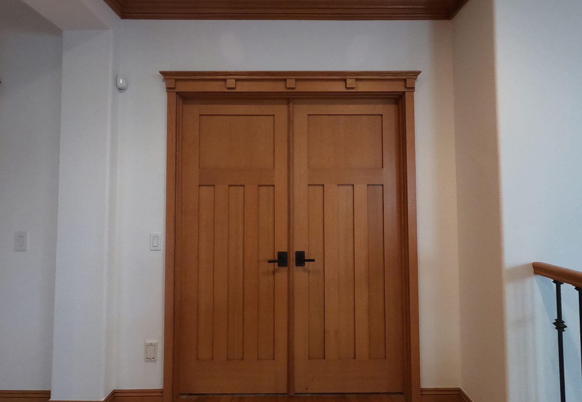 Built-in white media center with TV, fireplace, and shelves with wood backing; a person on screen.