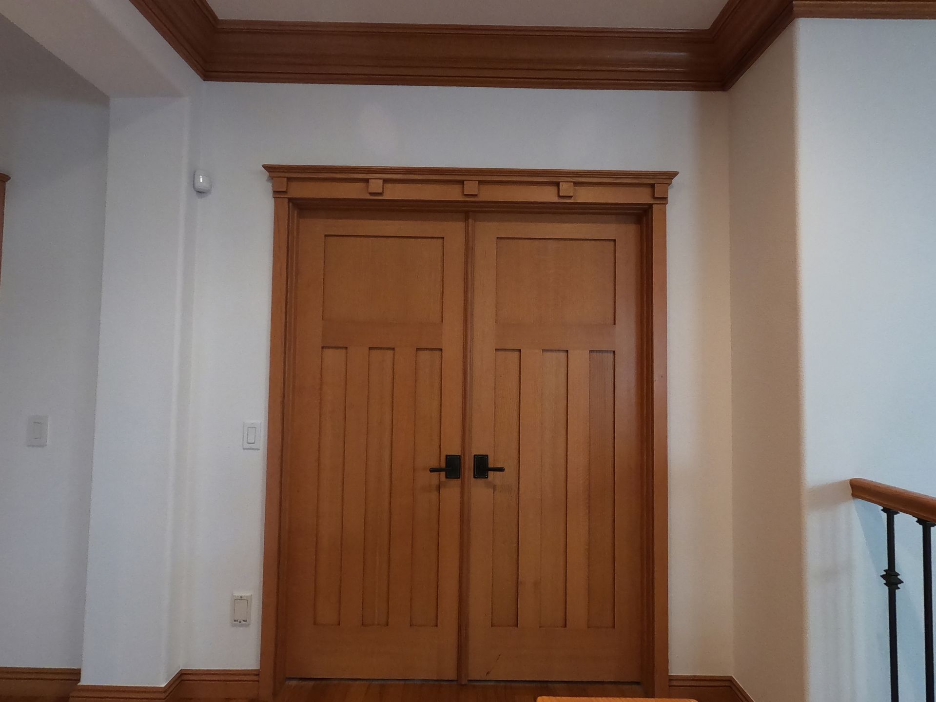 Wooden double doors with decorative molding in a hallway.