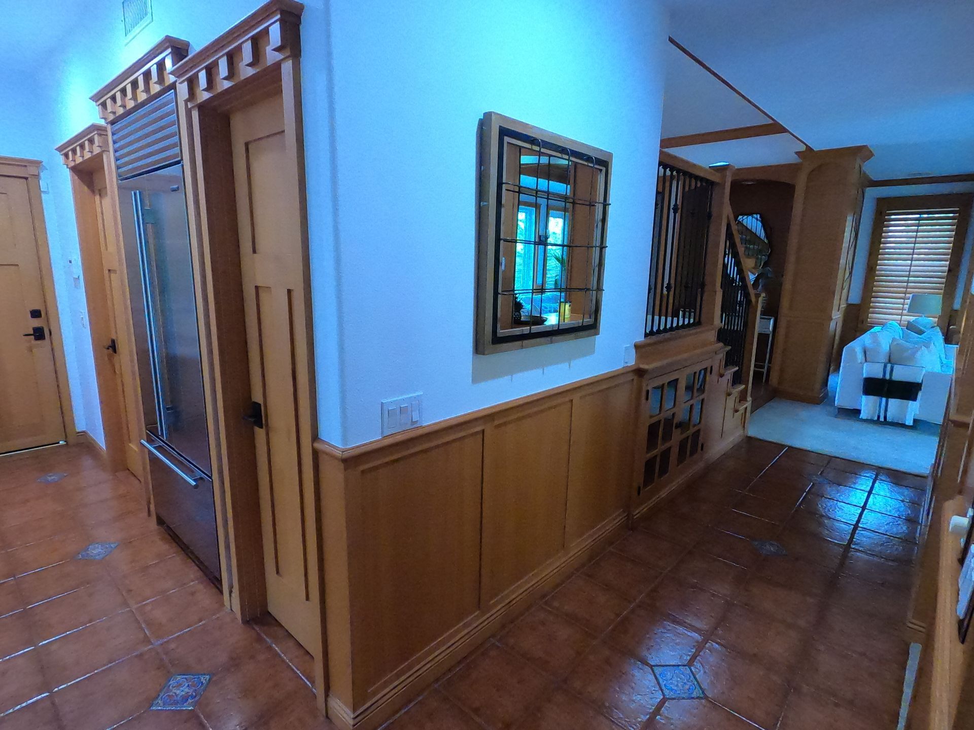 Hallway with tile floor, wood paneling and cabinetry, and a mirror.