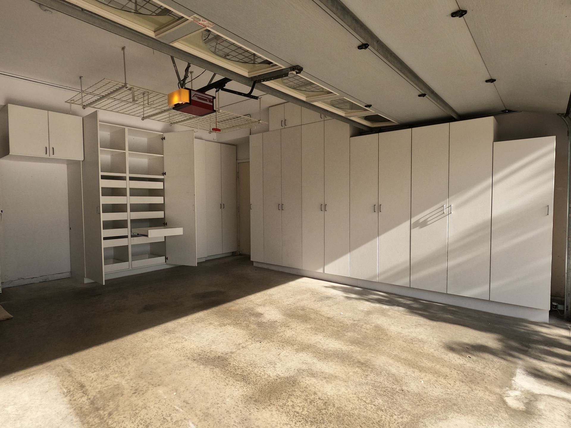 Empty garage with white storage cabinets and a concrete floor.